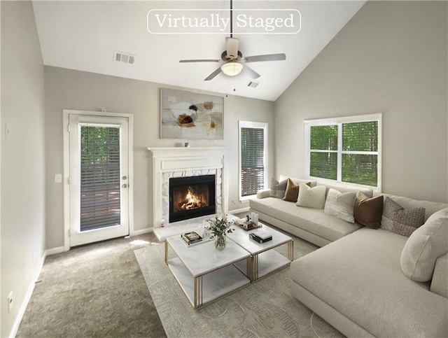 carpeted living room with lofted ceiling, a high end fireplace, and ceiling fan