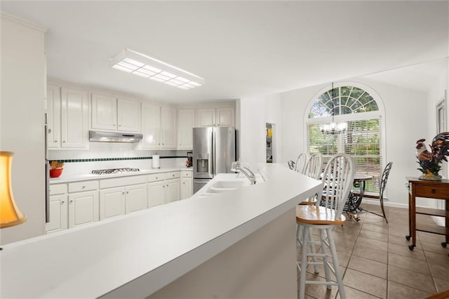 1418 Mill Path Loop, Lawrenceville, GA 30045 - kitchen with under cabinet range hood, gas stovetop, light countertops, a chandelier, and stainless steel fridge with ice dispenser