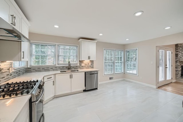 kitchen featuring decorative backsplash, white cabinets, appliances with stainless steel finishes, light countertops, and a sink