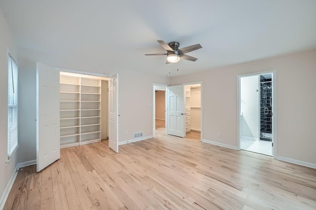 unfurnished bedroom with a spacious closet, a closet, visible vents, and light wood-style floors