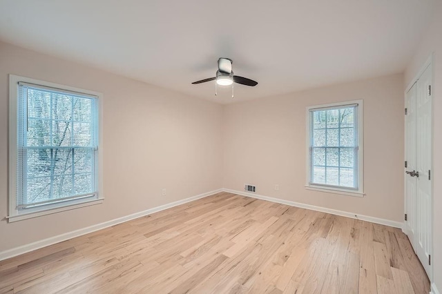 spare room with a ceiling fan, visible vents, light wood-style flooring, and baseboards