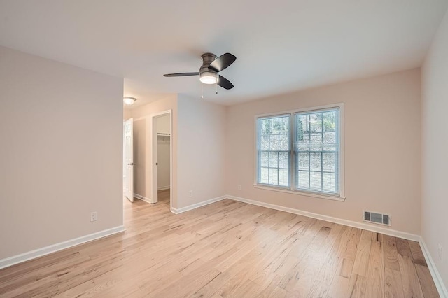 unfurnished room featuring a ceiling fan, light wood-type flooring, visible vents, and baseboards