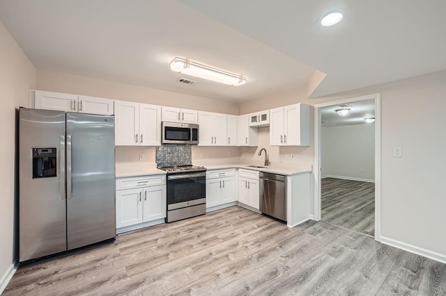 kitchen with stainless steel appliances, light countertops, a sink, and white cabinetry