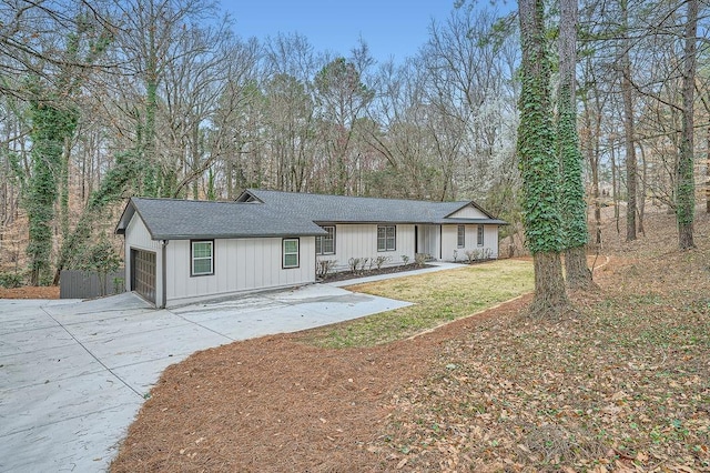 view of front facade with a garage, concrete driveway, roof with shingles, a front lawn, and board and batten siding