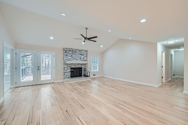 unfurnished living room featuring baseboards, a tiled fireplace, vaulted ceiling, french doors, and light wood-type flooring