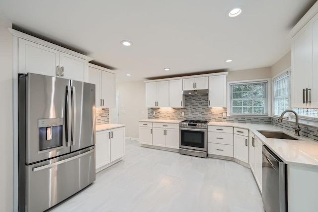 kitchen with white cabinetry, stainless steel appliances, a sink, and light countertops