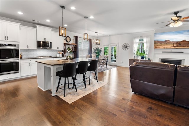 216 Orchard Trl, Canton, GA 30115 - kitchen with stainless steel appliances, a sink, open floor plan, a breakfast bar area, and dark wood-style flooring