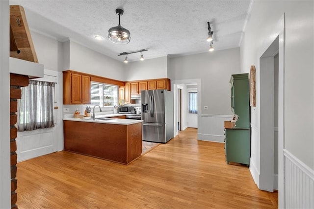 1238 Macland Rd, Dallas, GA 30132 - kitchen with stainless steel appliances, a peninsula, brown cabinetry, light countertops, and wainscoting
