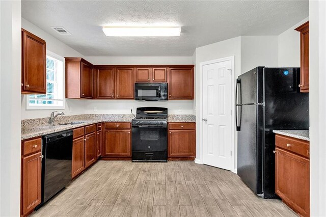 2146 Silva Ct, Conley, GA 30288 - kitchen featuring black appliances, light wood-type flooring, a sink, brown cabinetry, and a textured ceiling