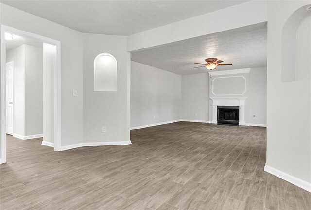 2146 Silva Ct, Conley, GA 30288 - unfurnished living room with a ceiling fan, baseboards, wood finished floors, a fireplace, and a textured ceiling