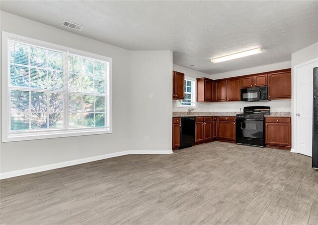 2146 Silva Ct, Conley, GA 30288 - kitchen featuring black appliances, light wood-type flooring, light countertops, baseboards, and a textured ceiling