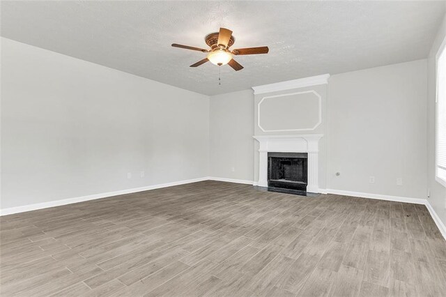 2146 Silva Ct, Conley, GA 30288 - unfurnished living room with ceiling fan, wood finished floors, baseboards, a fireplace, and a textured ceiling