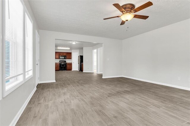 2146 Silva Ct, Conley, GA 30288 - unfurnished living room featuring light wood-type flooring, a ceiling fan, baseboards, and a textured ceiling
