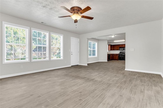 2146 Silva Ct, Conley, GA 30288 - unfurnished living room with ceiling fan, light wood-style flooring, baseboards, and a textured ceiling