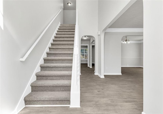 2146 Silva Ct, Conley, GA 30288 - staircase with wood finished floors, crown molding, arched walkways, baseboards, and a chandelier