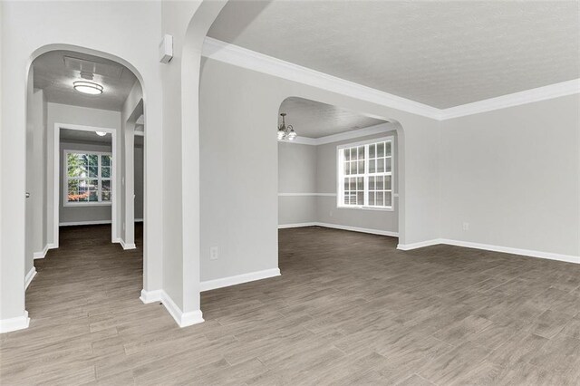 2146 Silva Ct, Conley, GA 30288 - empty room with wood finished floors, a textured ceiling, baseboards, arched walkways, and crown molding