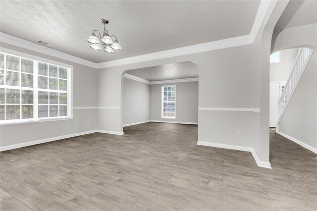 2146 Silva Ct, Conley, GA 30288 - unfurnished room featuring arched walkways, a chandelier, ornamental molding, wood finished floors, and a textured ceiling