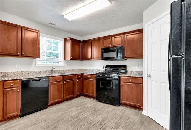 2146 Silva Ct, Conley, GA 30288 - kitchen featuring black appliances, light wood-style floors, a sink, light stone countertops, and a textured ceiling