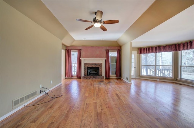 unfurnished living room with ceiling fan, vaulted ceiling, light hardwood / wood-style flooring, and a fireplace