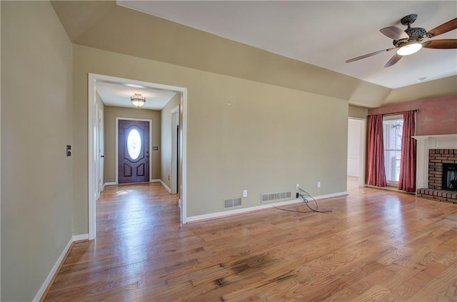 unfurnished living room featuring a brick fireplace, light hardwood / wood-style floors, and ceiling fan