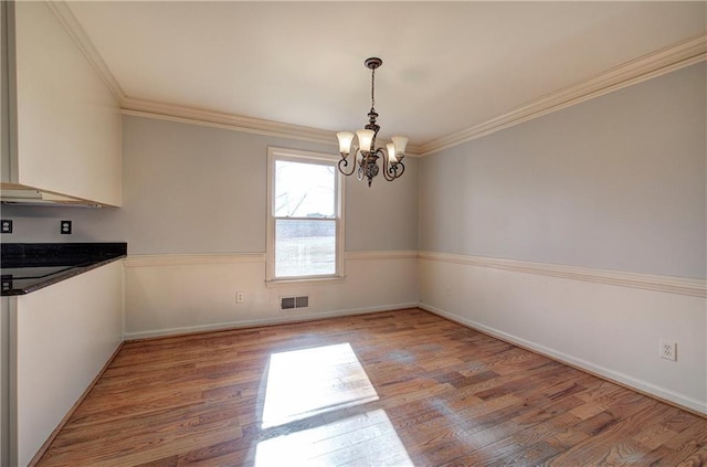 unfurnished dining area featuring a notable chandelier, ornamental molding, and light hardwood / wood-style floors