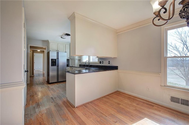 kitchen with white cabinetry, sink, stainless steel fridge, kitchen peninsula, and light hardwood / wood-style flooring