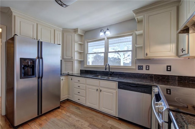 kitchen with wall chimney range hood, sink, light hardwood / wood-style flooring, appliances with stainless steel finishes, and white cabinets