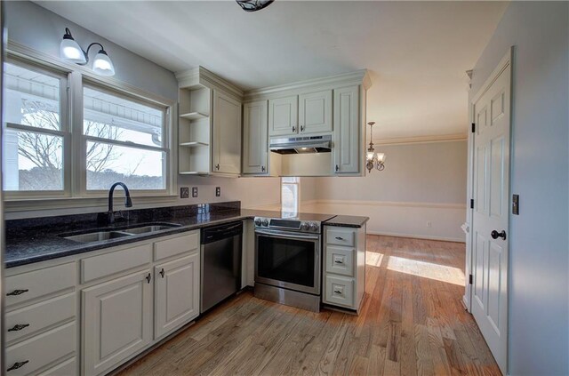 kitchen featuring appliances with stainless steel finishes, decorative light fixtures, sink, kitchen peninsula, and light wood-type flooring