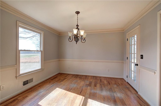 unfurnished dining area with a notable chandelier, crown molding, and hardwood / wood-style floors