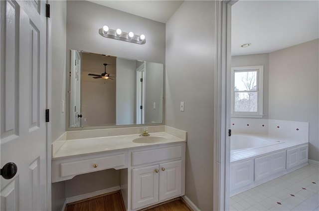 bathroom featuring ceiling fan, a washtub, and vanity