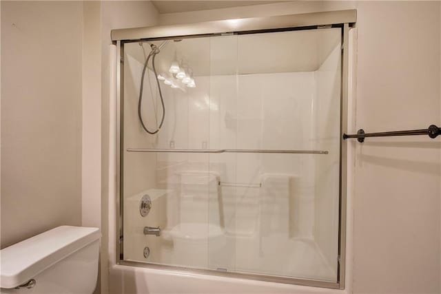 bathroom with bath / shower combo with glass door and toilet