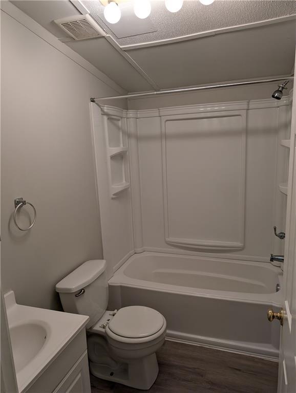 bathroom with bathing tub / shower combination, vanity, toilet, and wood finished floors