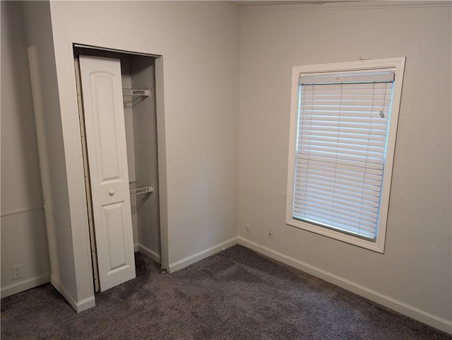 unfurnished bedroom with baseboards, a closet, and dark colored carpet