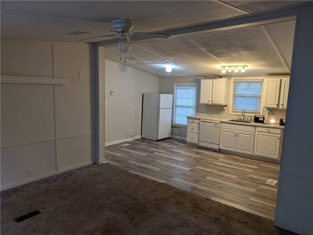 kitchen with white appliances, ceiling fan, light countertops, white cabinets, and a sink