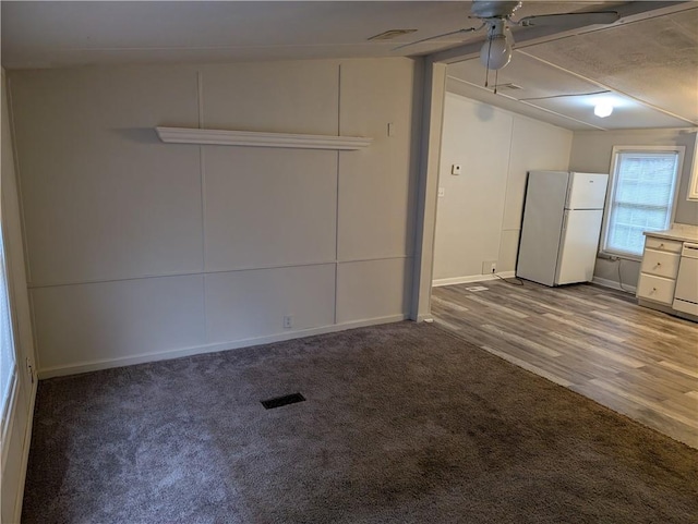 garage featuring baseboards, freestanding refrigerator, a ceiling fan, and visible vents