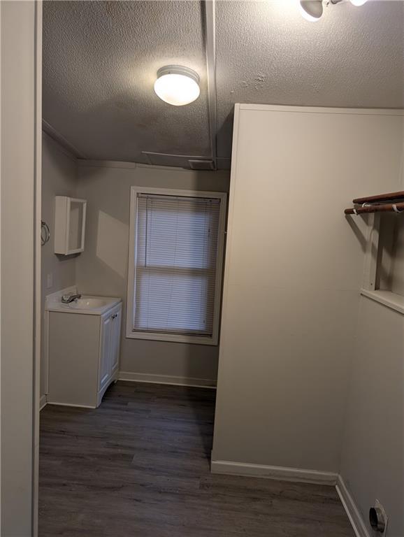 laundry room with baseboards, dark wood-style flooring, and a textured ceiling