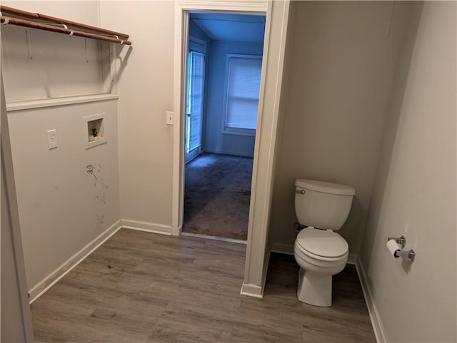 laundry area featuring washer hookup, baseboards, and wood finished floors
