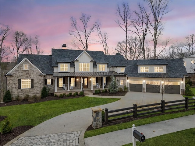 modern farmhouse style home with a fenced front yard, a chimney, a porch, a standing seam roof, and driveway