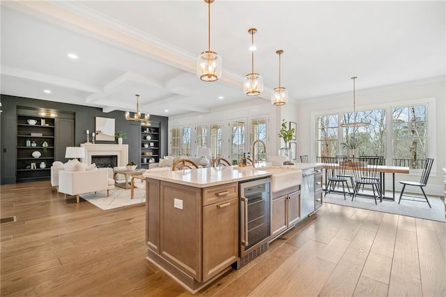 kitchen with wine cooler, ornamental molding, a sink, light wood-type flooring, and a fireplace