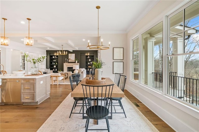 dining room with baseboards, wood finished floors, a chandelier, and crown molding