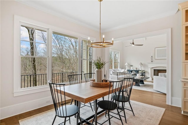 dining room with ceiling fan with notable chandelier, baseboards, wood finished floors, and ornamental molding