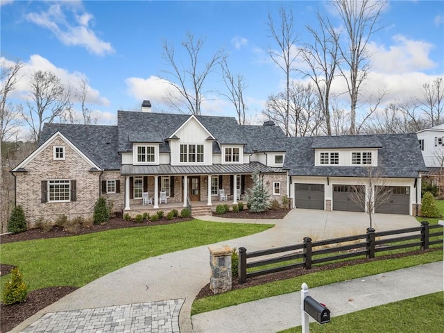view of front of home with a front lawn, a standing seam roof, driveway, fence private yard, and a porch