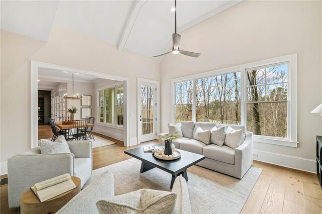 living area featuring a wealth of natural light, vaulted ceiling with beams, and light wood-type flooring