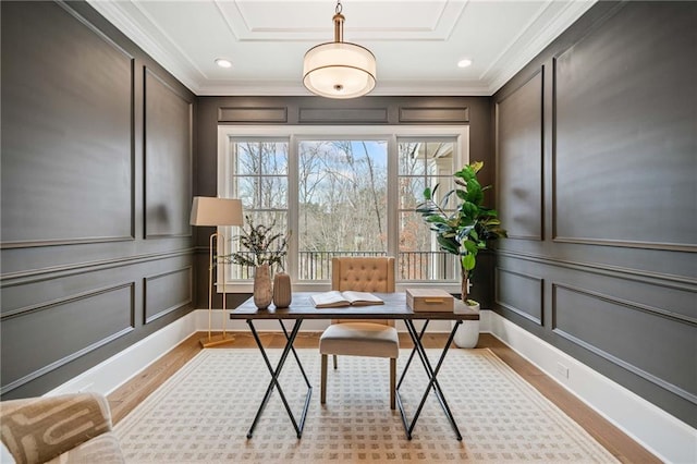 office area featuring a decorative wall, ornamental molding, and light wood-style floors