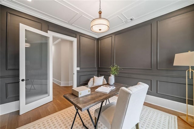 office area with light wood-style flooring, a decorative wall, and baseboards