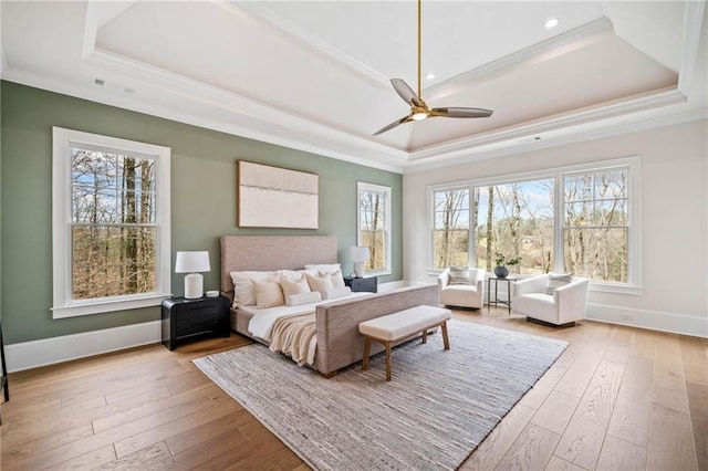 bedroom featuring wood-type flooring, baseboards, crown molding, and a raised ceiling
