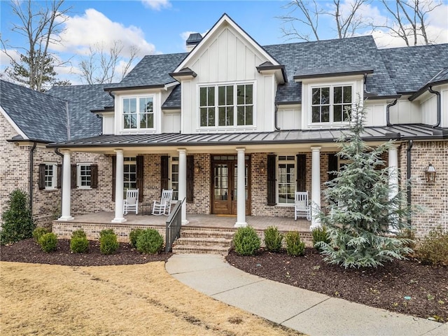 modern inspired farmhouse featuring a chimney, a standing seam roof, a porch, board and batten siding, and brick siding