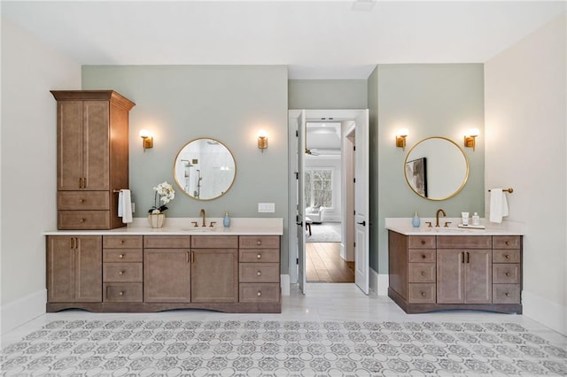 full bath featuring two vanities, baseboards, and a sink