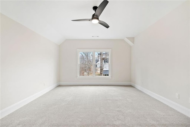 spare room with lofted ceiling, a ceiling fan, baseboards, and light carpet
