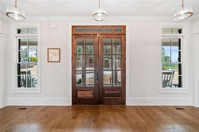 foyer featuring hardwood / wood-style floors, visible vents, crown molding, and french doors